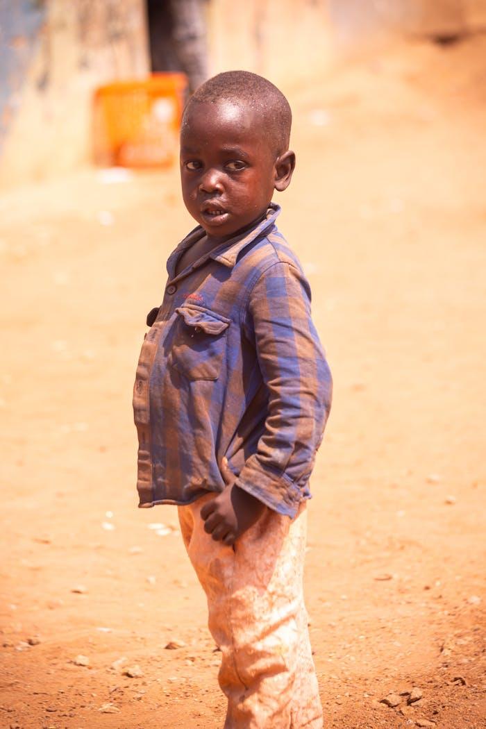 services-01 A young child stands outdoors in casual attire on a sunny day, looking directly at the camera.